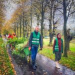 Mensen lopen door een bomenlaan met kruiwagens vol zaailingen
